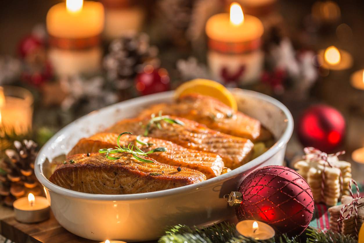 Christmas dinner from fish salmon in roasting dish with festive decoration advent wreath and 
